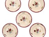 four plates with flowers painted on them sitting on a white surface