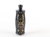 a black vase with a gold design on it