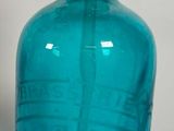 une bouteille en verre bleu munie d'une pompe en métal sur le dessus