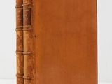 an old book with a brown leather cover sitting on a white surface