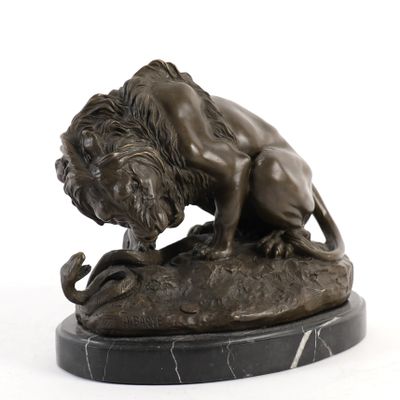 statue d'un lion perché sur un rocher, tenant un serpent dans la gueule