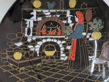 a decorative plate with a picture of a woman in front of a fireplace