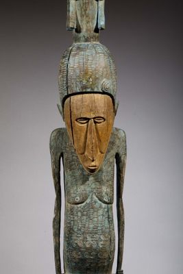 une image représentant une statue en bois d'un homme avec un oiseau sur la tête