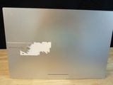 the back of a silver laptop sitting on top of a wooden table