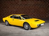 a yellow car that is parked in front of a brick wall