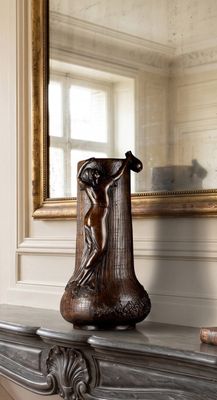 a vase that is sitting on a mantle in front of a mirror