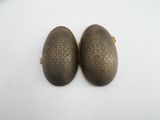 two oval metal objects sitting on a white surface