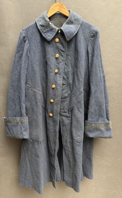 an old blue coat hanging on a wall next to a wooden hanger
