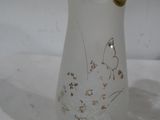 un vase en verre avec un papillon sur une surface blanche