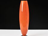 un vase orange posé sur une table blanche