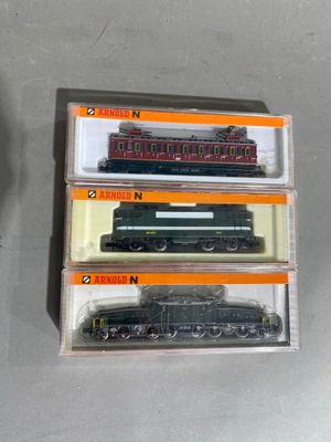 trois trains miniatures dans leurs boîtes, empilés les uns sur les autres sur une table