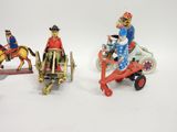 three figurines of a man riding a horse drawn carriage and a man on a horse drawn carriage
