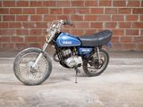 a small blue motorcycle parked in front of a brick wall