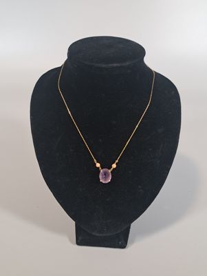 un collier orné d'une pierre violette sur un mannequin noir