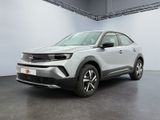 a silver car parked in a garage with a white wall behind it