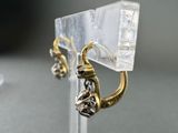 a pair of earrings that are sitting on a stand