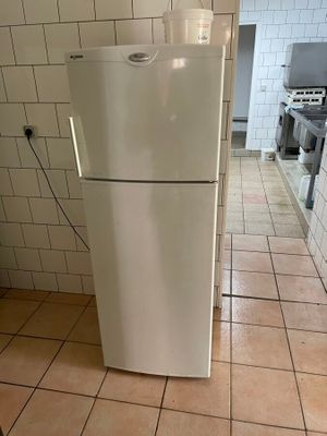 un réfrigérateur blanc dans une cuisine au sol carrelé