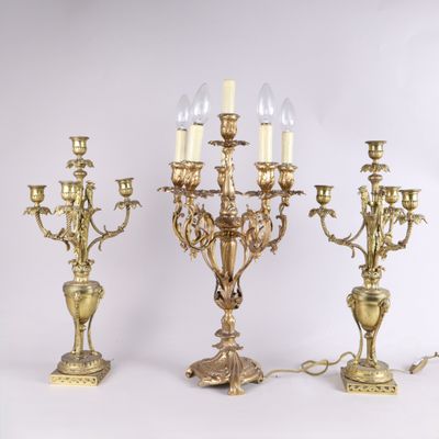 trois chandeliers anciens en laiton, chacun orné de bougies