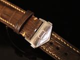 a close up of a watch on a black surface with a black background