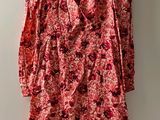 une robe à fleurs rouges suspendue à un cintre devant un mur blanc