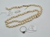 a close up of a necklace with pearls and a ring on a table