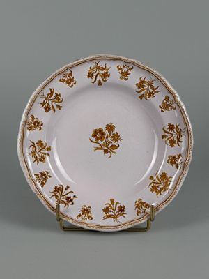 MOUSTIERS. Assiette en faïence à décor en camaïeu ocre de fl…