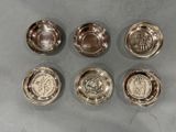 six bols en métal argenté, ornés de motifs différents, posés sur une table