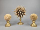 trois vases en or ornés de coquillages, posés sur une table