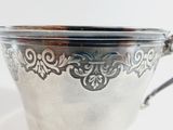 an antique silver plated cup with a handle on a white surface