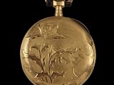 a gold pocket watch with a floral design on it