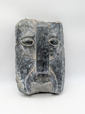a stone sculpture of a face on a white background