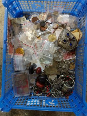 un panier bleu posé par terre, rempli d'objets divers