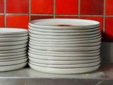 several stacks of plates are stacked on a counter in a kitchen