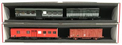 deux wagons rouges dans une boîte posée sur une surface blanche