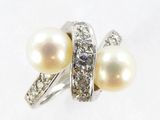 une image représentant une bague ornée de perles et de diamants sur un fond blanc