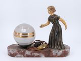 a figurine of a woman standing next to a crystal ball