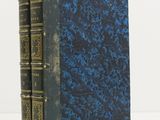 un livre bleu et noir avec des bordures dorées sur une couverture blanche