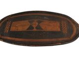 an old wooden tray with a black and brown design on it