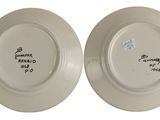 two white plates with black writing on them sitting side by side