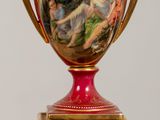 a red vase with a painting on it sitting on a table