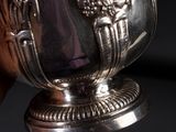someone is holding a silver cup with a handle in their hand