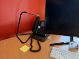 a computer monitor and keyboard on a desk in front of a red wall