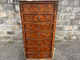 une commode ancienne posée sur le trottoir, près d'un mur de pierre