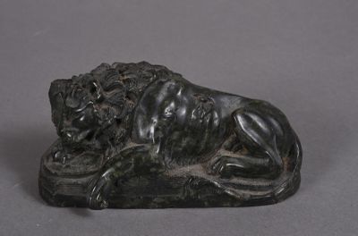 statue d'un lion posé sur un rocher, sur un fond gris