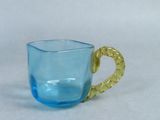 a blue glass cup with a gold handle sitting on a table
