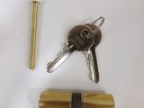 two keys and a brass lock on a white surface