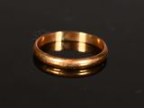 a gold wedding ring on a black surface