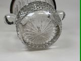 a glass vase with a handle on a white surface