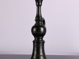 a black vase sitting on a table with a white wall in the background