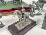 several figurines of men on horses and carriages on a table